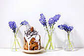 Homemade traditionla Easter kulich cake with chocolate nests and eggs, decorated with muscari flowers