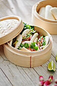 Tasty steamed baozi buns with radish and cucumber slices with meat and fresh cilantro