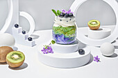 Glass jar of chia pudding with kiwi decorated with blueberries and flowers