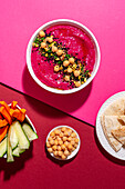 Beetroot hummus garnished with chickpea served on two colored background