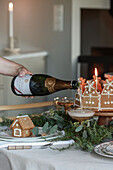 Einschenken in Champagnerschalen auf weihnachtlich gedecktem Tisch