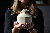 A woman holding a ready-to-drink cut coconut