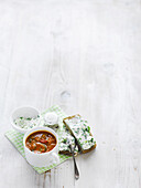 Chunky Mediterranean tomato soup, served with herby ricotta on rye bread