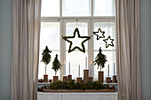 Window decoration with stars, mini fir trees and candles