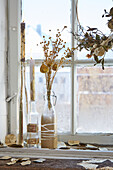 Dried flowers in glass bottles on windowsill