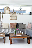 Living room with sofa, wooden tables and ceiling lamps