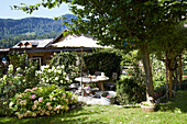 Idyllic garden with seating area and flowering beds in summer