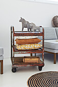 Metal serving trolley with decorative cushions and wooden horses next to sofa