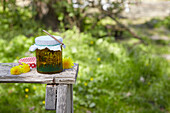 Selbstgemachtes Löwenzahnblüten-Öl auf Tisch im Garten