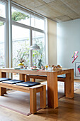 Solid wood table with benches and pendant light in light-colored dining room