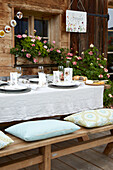 Outdoor table setting and wooden bench with cushions