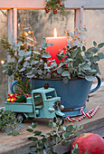 Vintage enamel bowl with eucalyptus and burning candle, toy truck in front of it