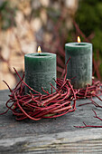 Brennende Kerze mit Kränzchen aus Hartriegel (Cornus)