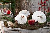 Ice ball with rose hips, cones and red candle
