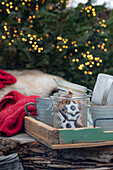 Glas mit Zimtsternen und Keramikbecher auf Holztablett