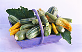 Basket with courgettes and courgette flowers on a light background