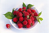 Raspberries with leaves in a bowl