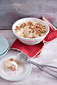 Walnut ice cream in a bowl and ice cream scoop on a small plate