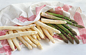 White and green asparagus spears on a red and white cloth