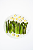 Green asparagus with leek slices on white plate