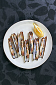 Grilled razor clams with lemon slice on white plate
