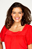 A brunette woman wearing a red blouse with a lace trim