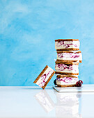 Marbled blackberry ice cream sandwiches stacked against a blue background