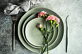Minimalistische Tischdekoration in grauen Farben, dekoriert mit rosa Nelken
