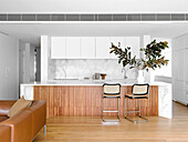 Marmor-Kücheninsel mit Klassiker-Barhockern in hellem, offenem Wohnraum