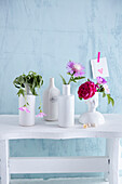 Weiße Vasen mit frischen Blüten, eine mit verwelker Blüte (Beschwerden, Kranksein)