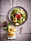 A salad with fried onion rings, feta, strawberries and grapes