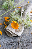 Linen napkin with marigolds (Calendula officinalis), and napkin ring made of clematis fruit stalks