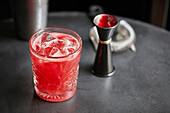Red cocktail in a glass with ice cubes