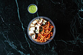 A healthy bowl with tofu and crispy sweet potato to take away