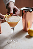 Whiskey-Sour-Cocktail mit Zitronenschale garnieren