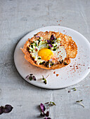 Rice flour wafer with fried egg, cucumber relish and shiso cress