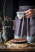 Tiramisu-Kuchen, im Hintergrund Frau mit Kaffeetasse