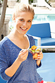 Blonde Frau in blauem Shirt mit Dessert in der Hand