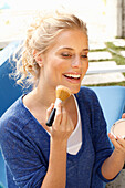 A blonde woman wearing a blue shirt applying makeup with brush