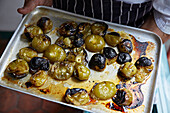 Roast tomatillos on a metal tray being prepared for salsa verde