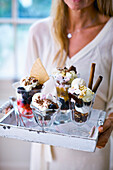 Woman serving a selection of ice cream sundaes on tray
