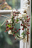 Small wreath of snowberries, rosehips and heather hanging on an antique window handle