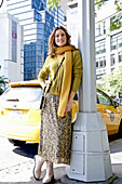 A long-haired woman wearing a scarf, a floral patterned skirt and a green cardigan