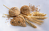Three wholemeal rolls, ears of cereal, and cereal grains