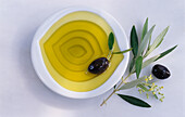 Bowl with olive oil, olives and an olive branch