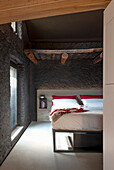 Bedroom with rustic stone wall and wooden beamed ceiling