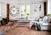 Bright living room with large wall clock, sofa, wooden coffee table and picture on the wall