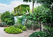 Bewachsenes Häuschen aus Recyclingmaterial und Staketenzaun im Garten (Appeltern, Niederlande)
