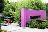 Pinkfarben Mauer als Trennelement, im Hintergrund Gartenplatz mit bunten Barhockern (Appeltern, Niederlande)