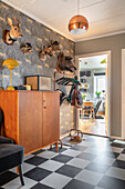 Stuffed animal heads on a wallpapered wall above a half-height cupboard